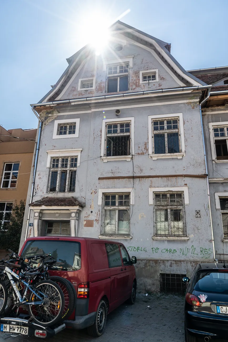 Altes Haus mit Sonnenlicht, roter Van und Fahrräder