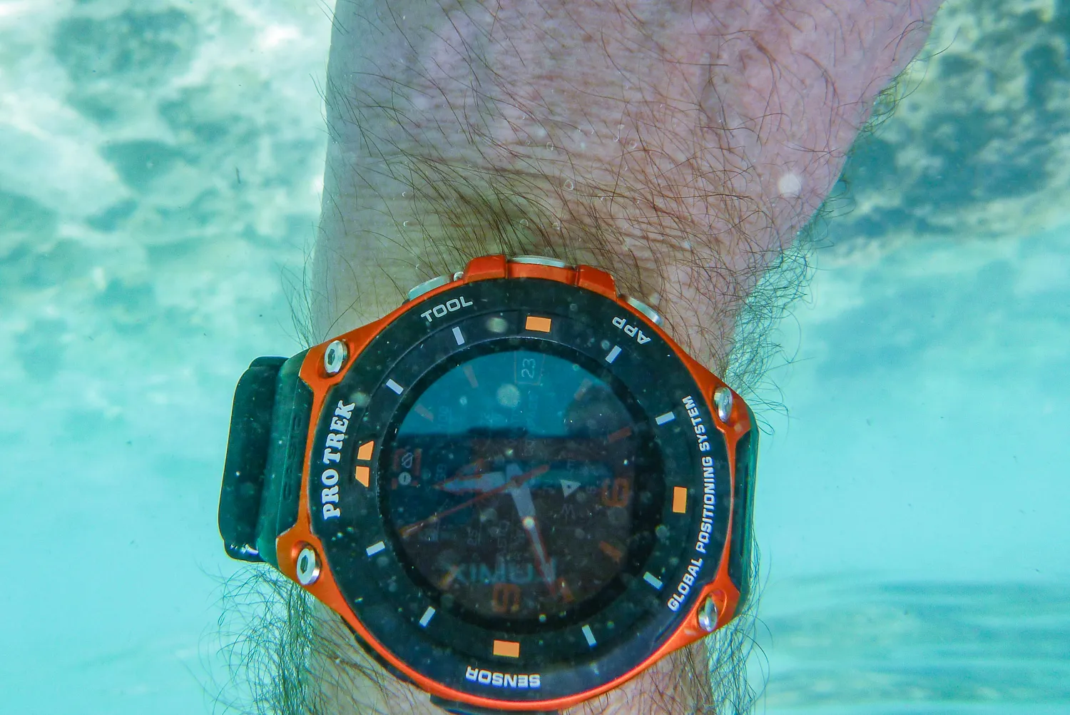 Unterwasserfoto einer orangefarbenen Armbanduhr am Handgelenk