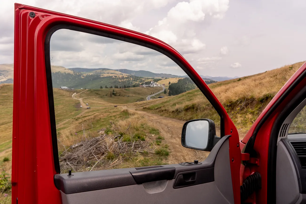 roter wagen mit offenem tür, berglandschaft im hintergrund