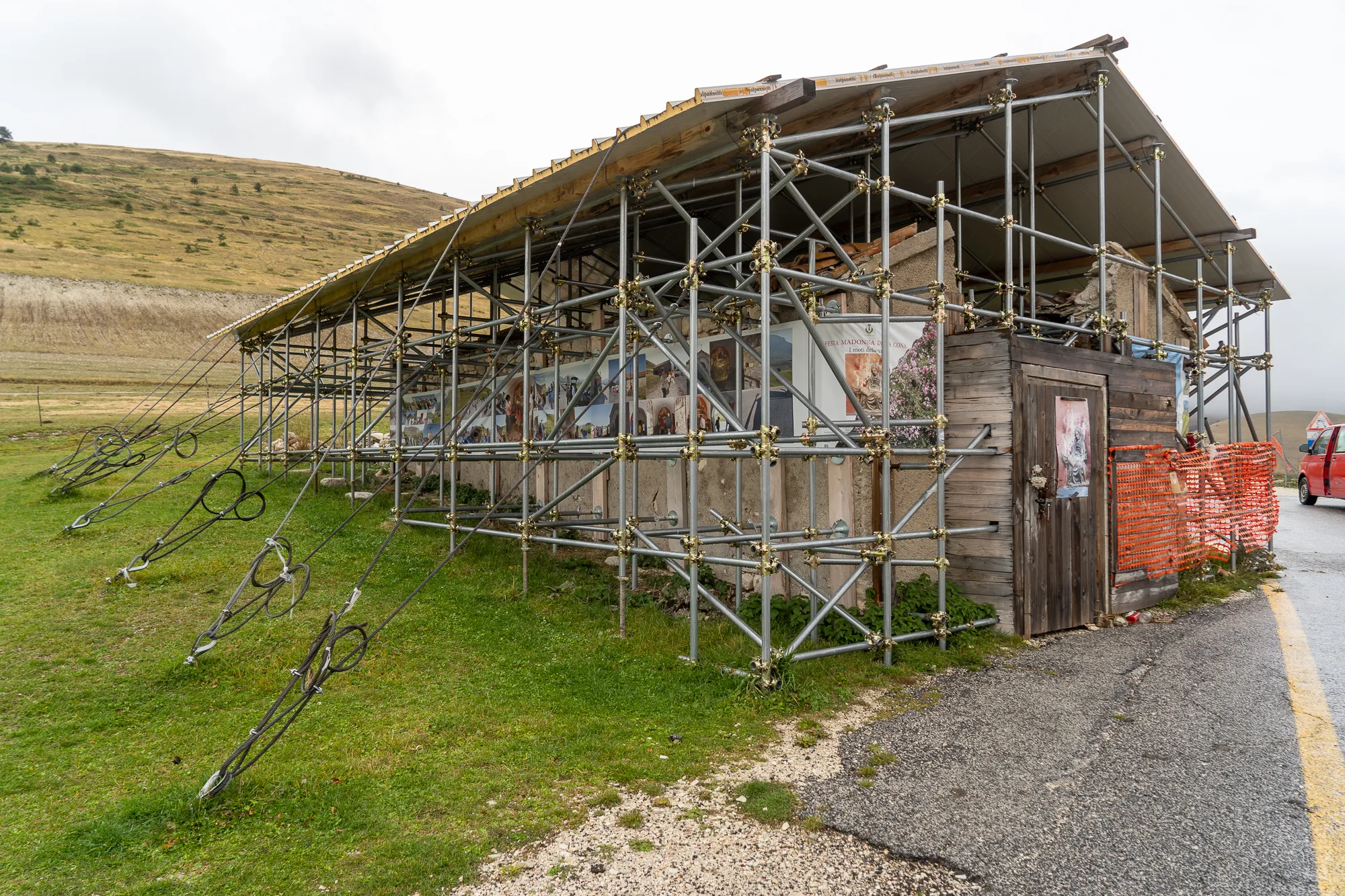 Baustelle mit Metallgerüst und Holzhaus in ländlicher Umgebung