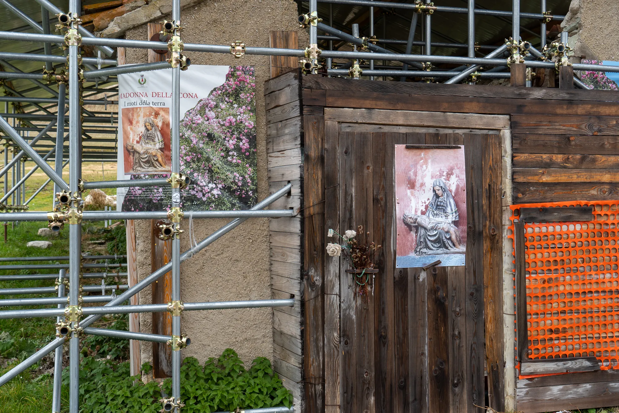 Baustelle mit Holztür und religiösen Bildern an einer Steinwand