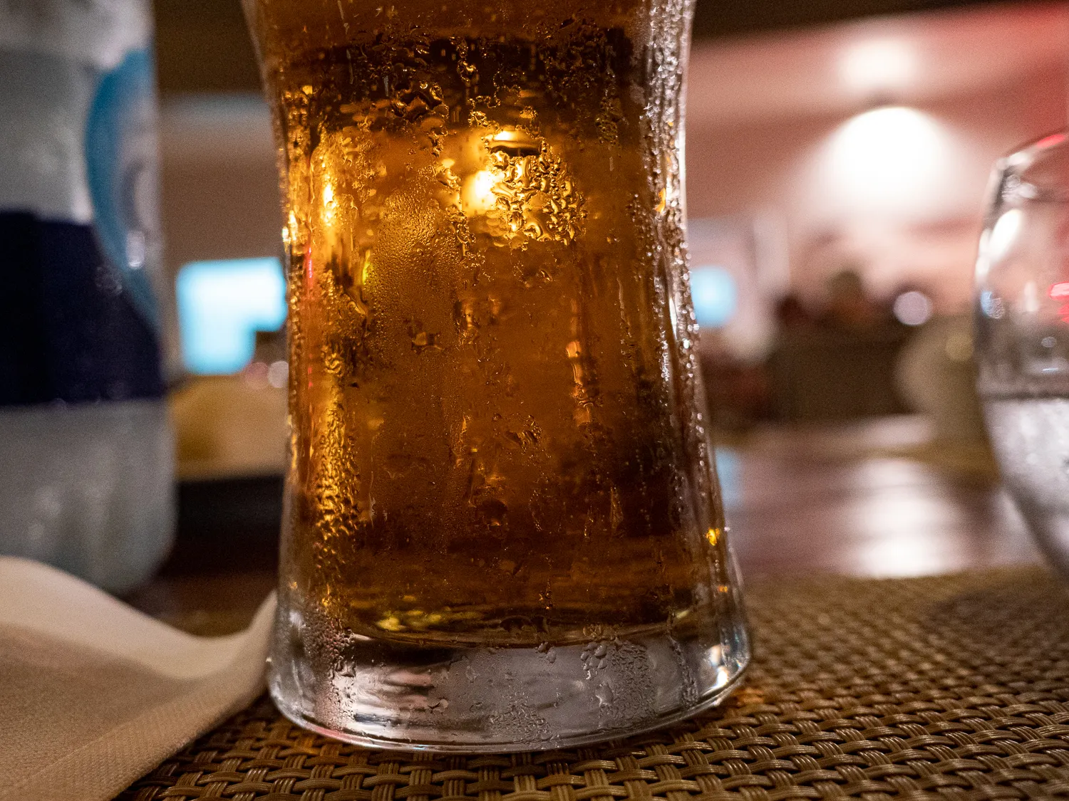 Kühles Bierglas mit Tropfen auf einem geflochtenen Tisch