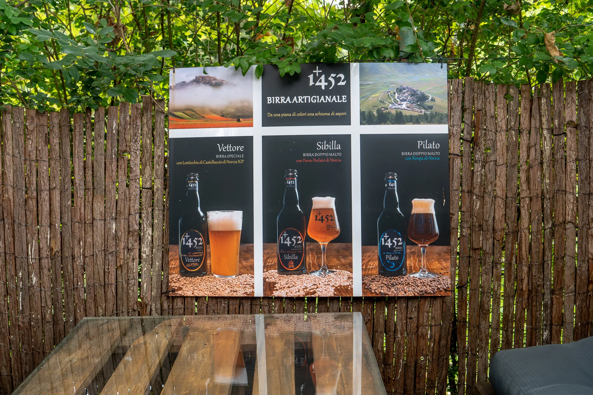 Bierwerbung mit drei Sorten vor Holzzaun und grünen Blättern