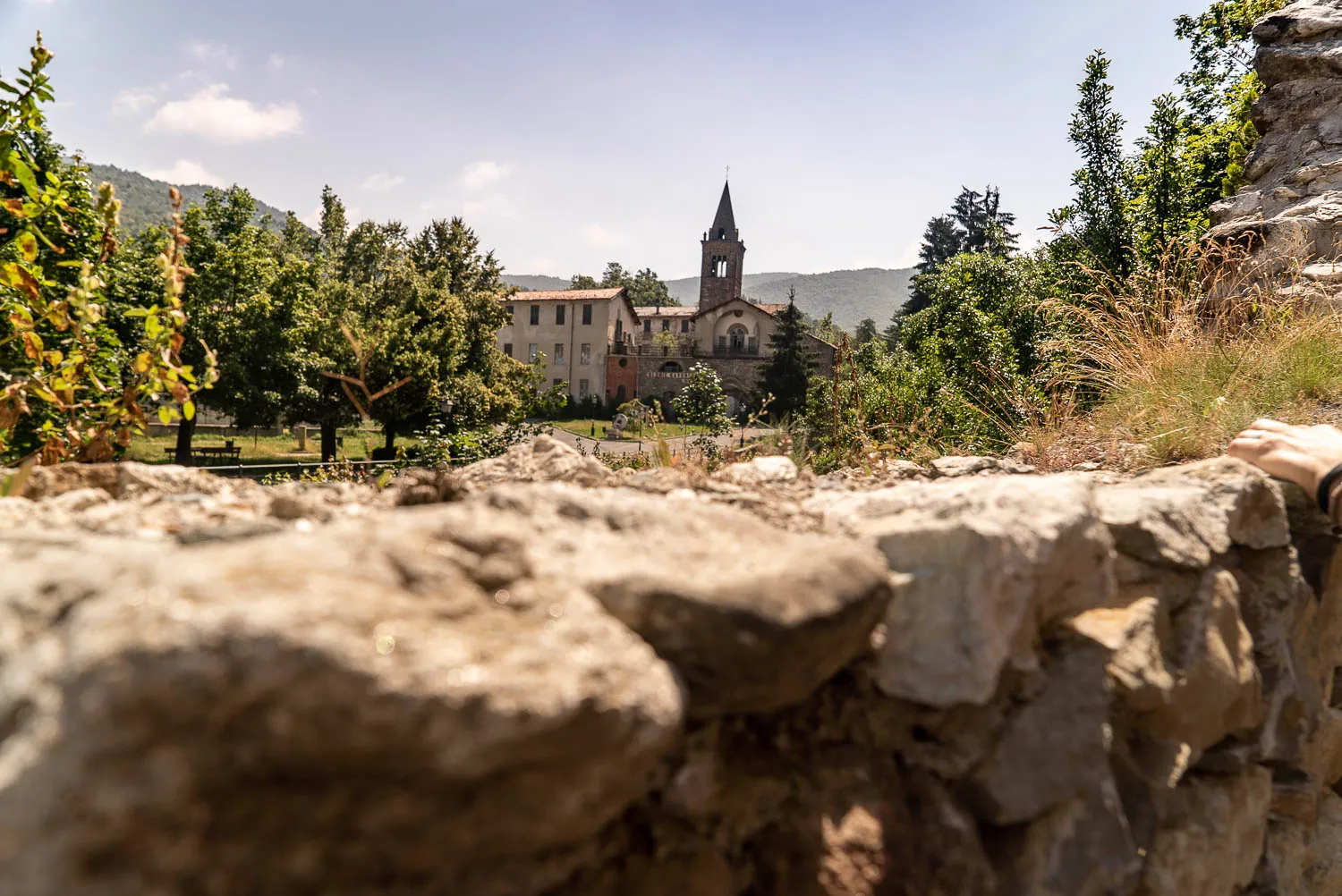 dorf mit kirche hinter steinmauer im vordergrund