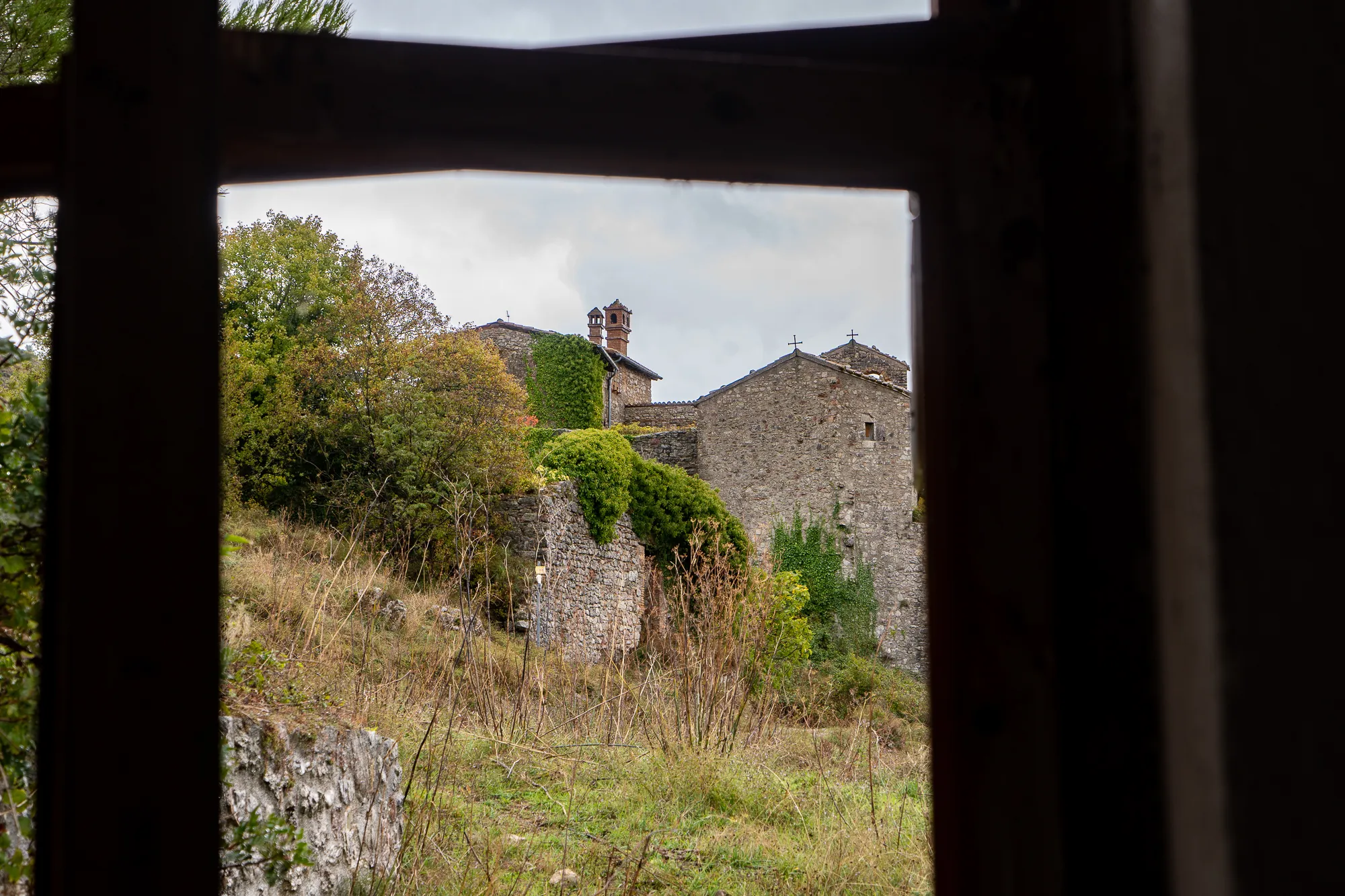 Dorfhäuser aus Stein mit Kletterpflanzen, gesehen durch ein Fenster