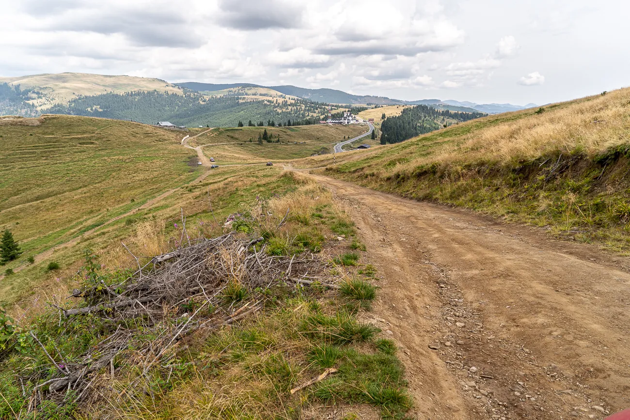 Dreckiger Weg durch grasbewachsenes Tal mit Hügeln im Hintergrund