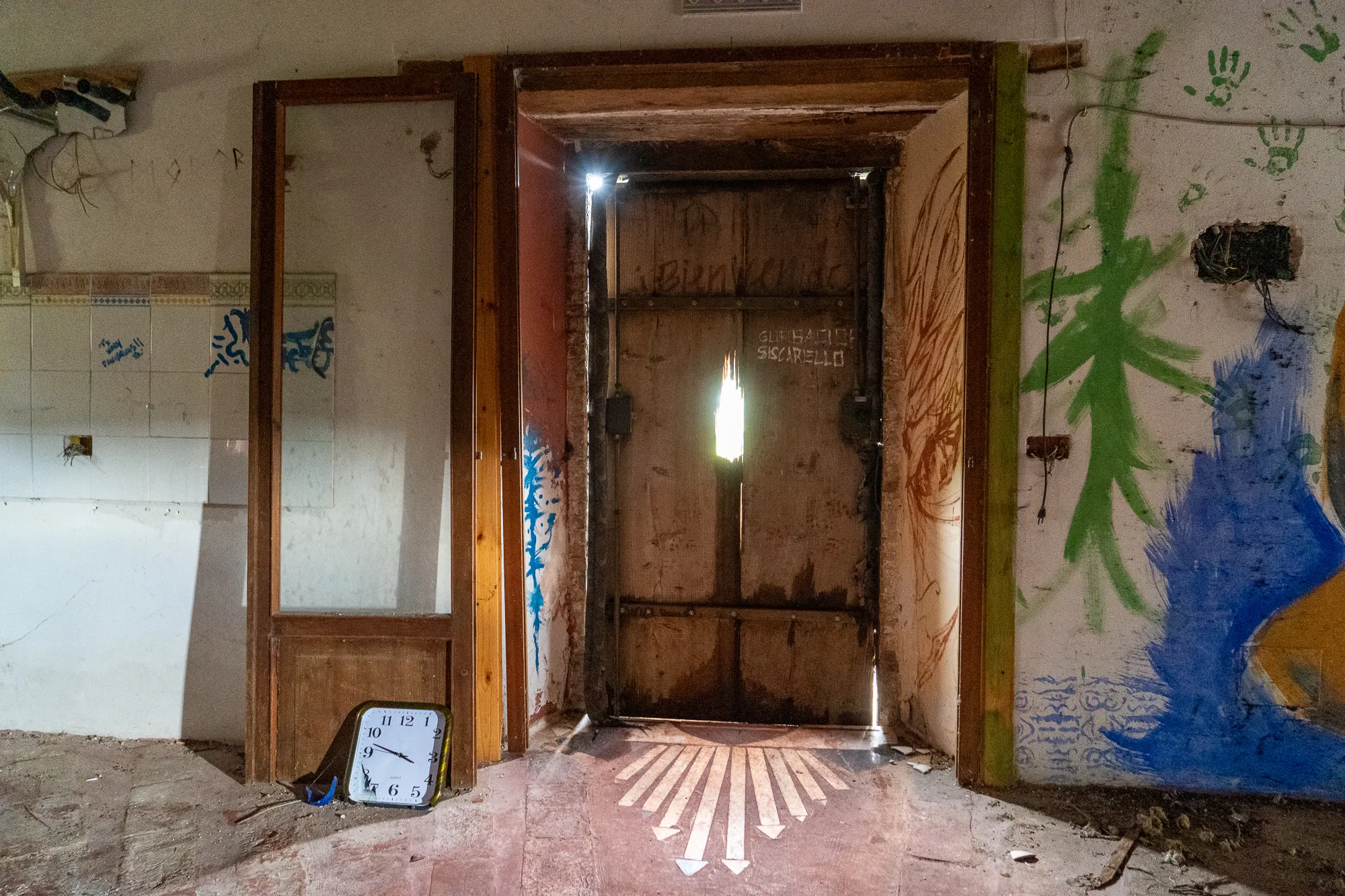 Eingangstür in verlassener Halle mit Graffiti und Wandmalereien