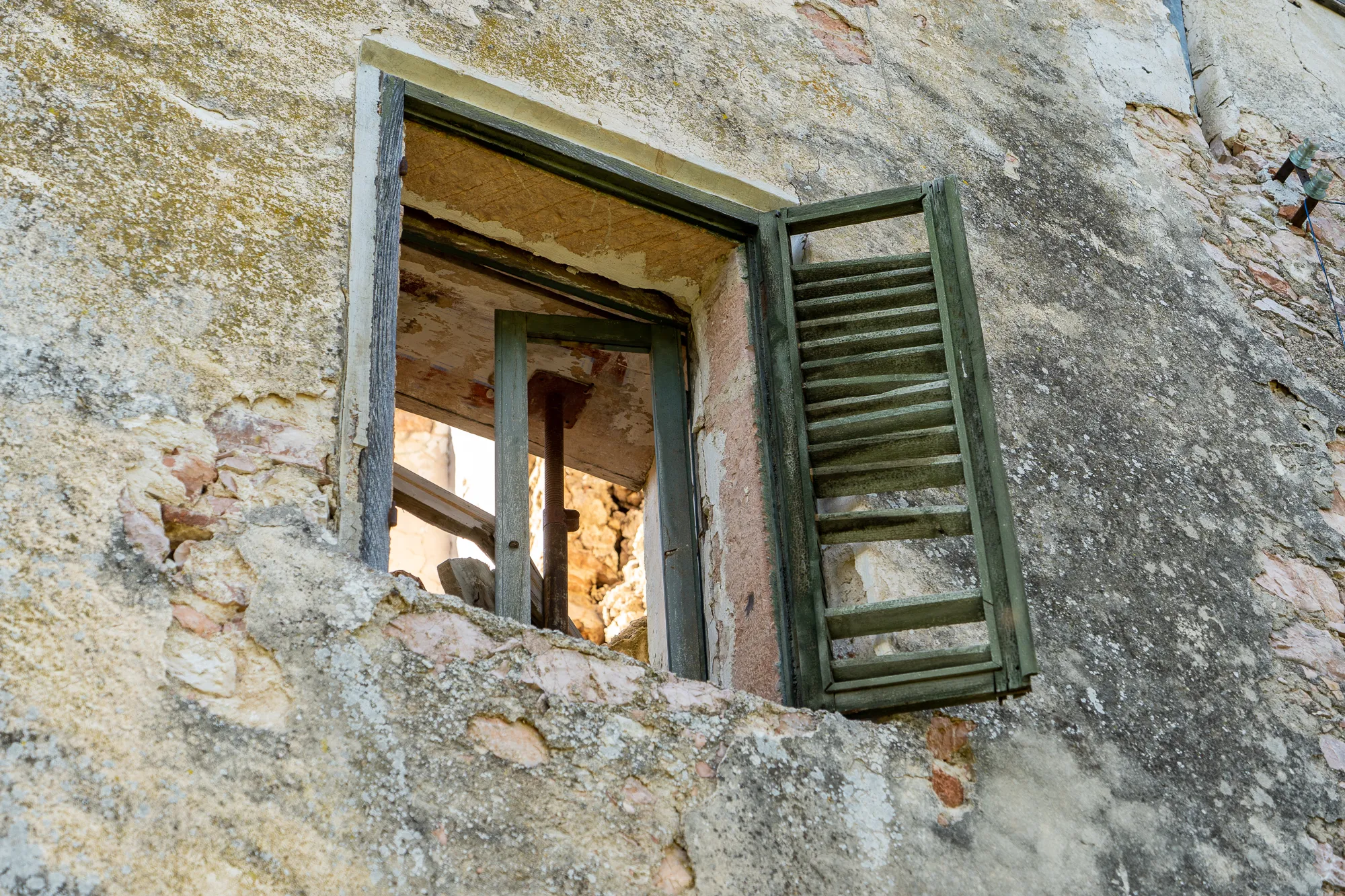 Altes Fenster mit grünen Läden in verwitterter Steinmauer