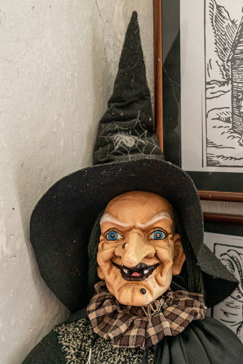 Hexenfigur mit spitzen hut und kariertem kragen an wand