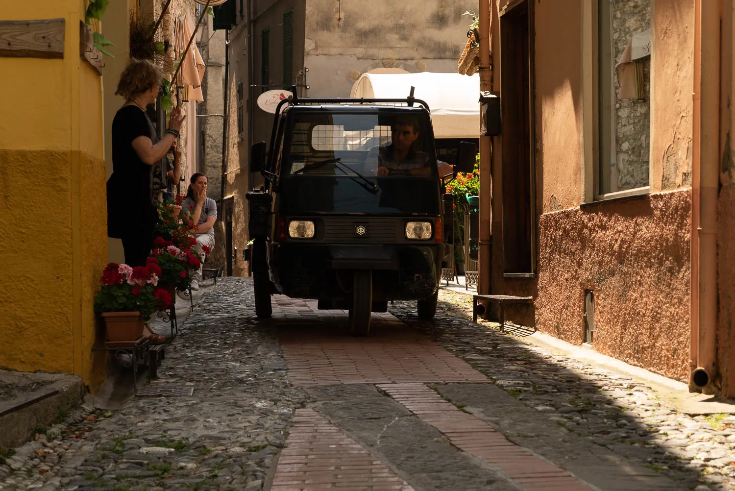 Schmalen Gassenweg mit Autoscooter und Blumenkübeln an Hauswänden