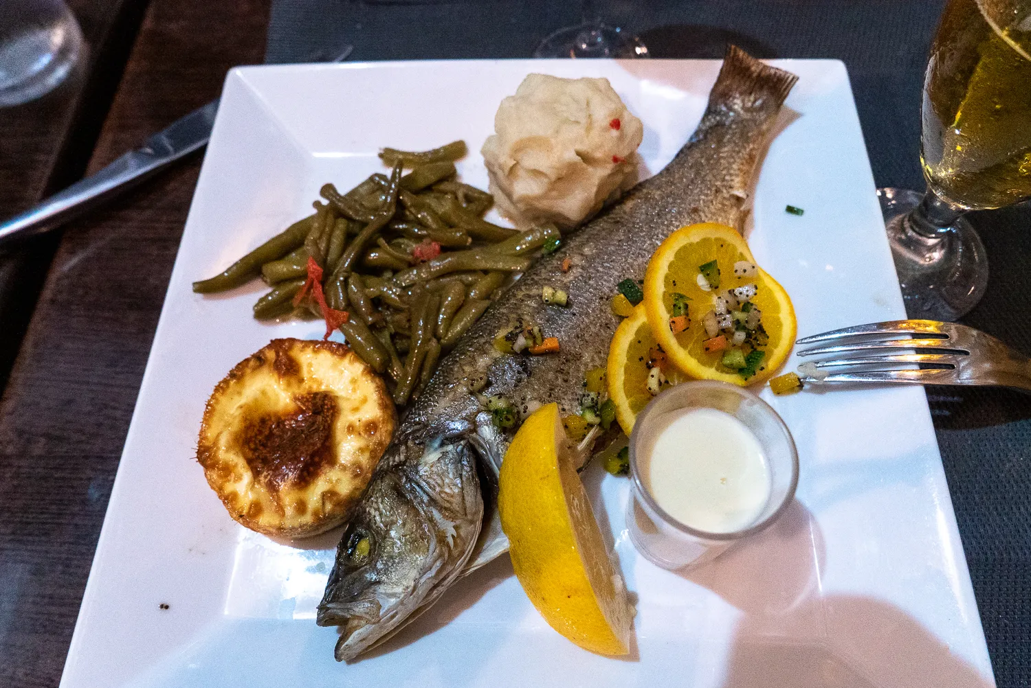 Gegrillter Fisch mit grünen Bohnen, Kartoffel und Zitronenscheiben auf Teller