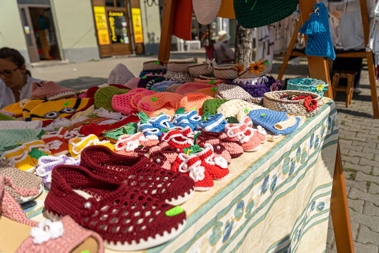 Farbenfrohe gehäkelte Schuhe und Accessoires auf einem Marktstand