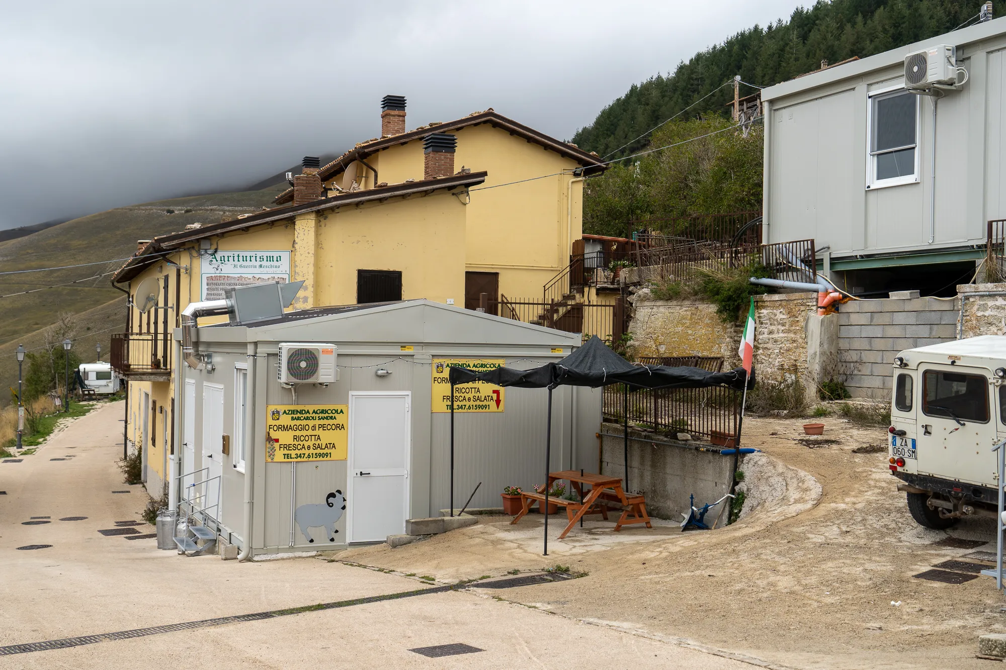 Gelbes Haus mit Schildern und Tischen im Dorf Castelluccio di Norcia