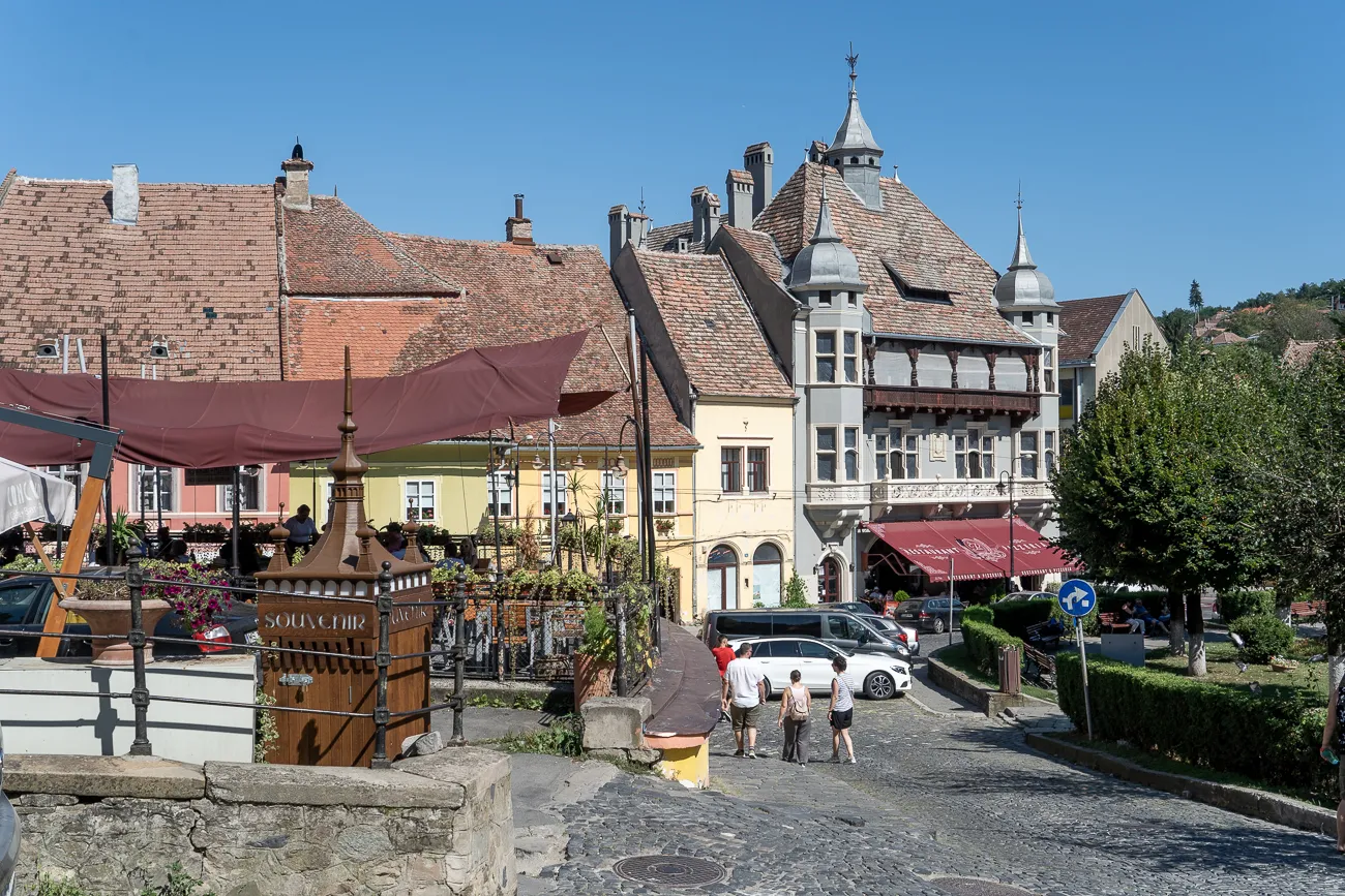 Straße mit historischen Häusern und Passanten unter blauem Himmel