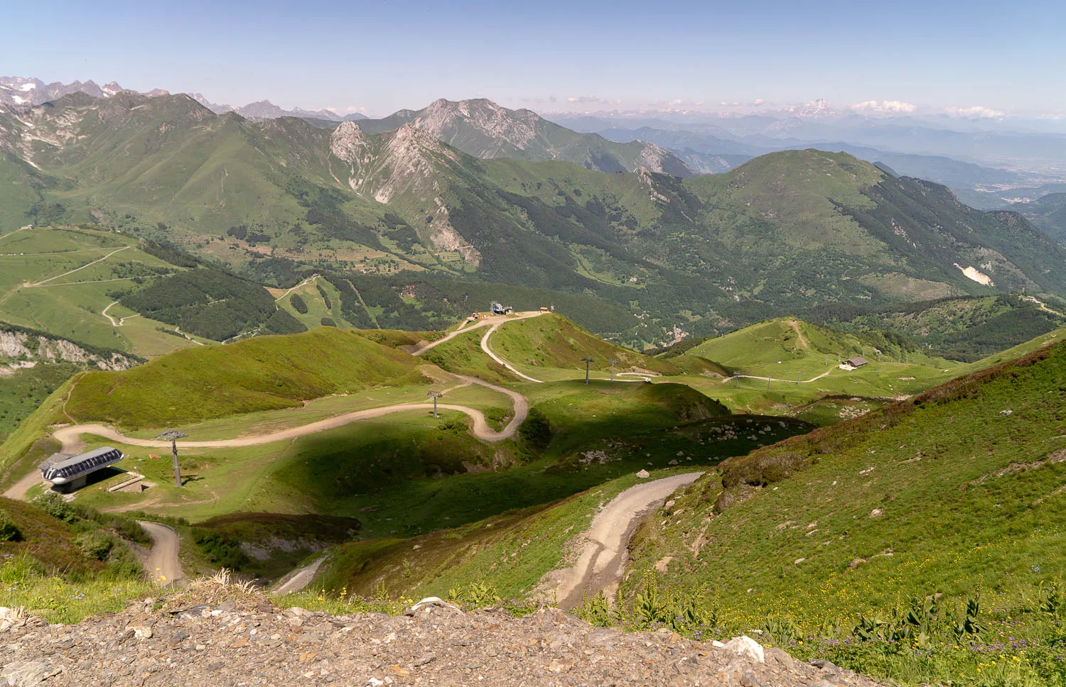 grüne berglandschaft mit schneebedeckten gipfeln und wiesenpfaden