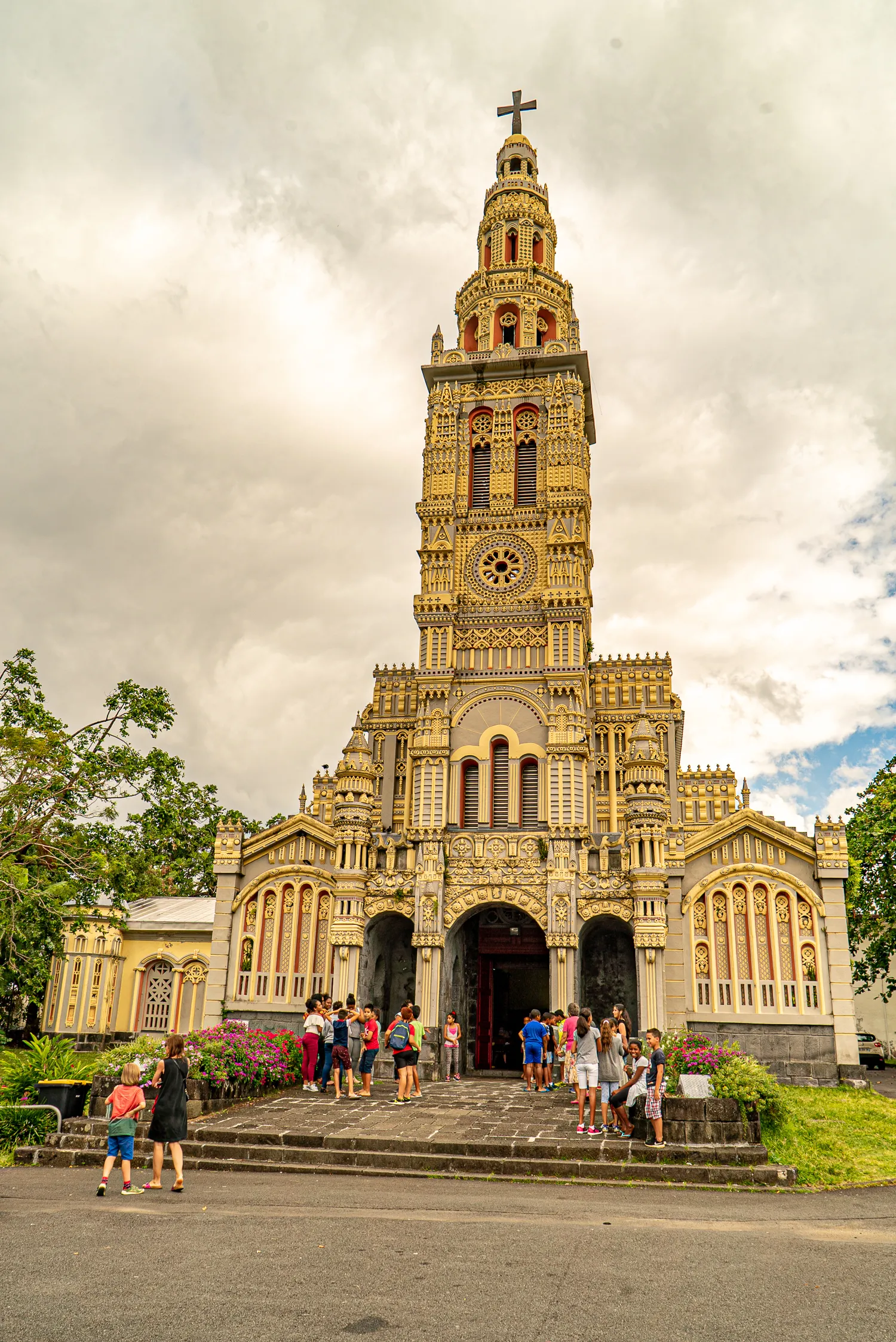 Große goldverzierte Kirche mit Turm und Besuchern vor Eingang