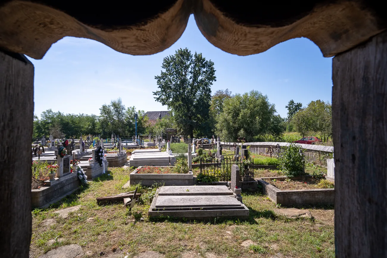 Grabsteine und Bäume im Friedhof durch hölzernes Fenster