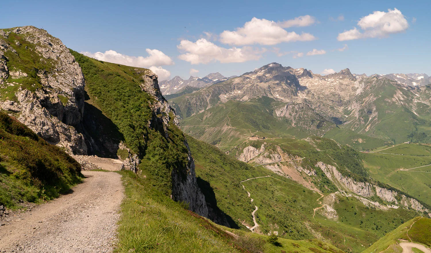 grauer steinweg durch grüne berglandschaft unter blauem himmel mit wolken