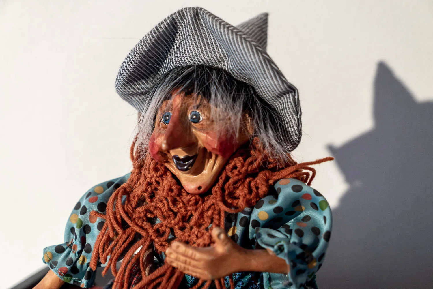 Holzfigur einer Hexe mit gestricktem Bart und gestreifter Mütze