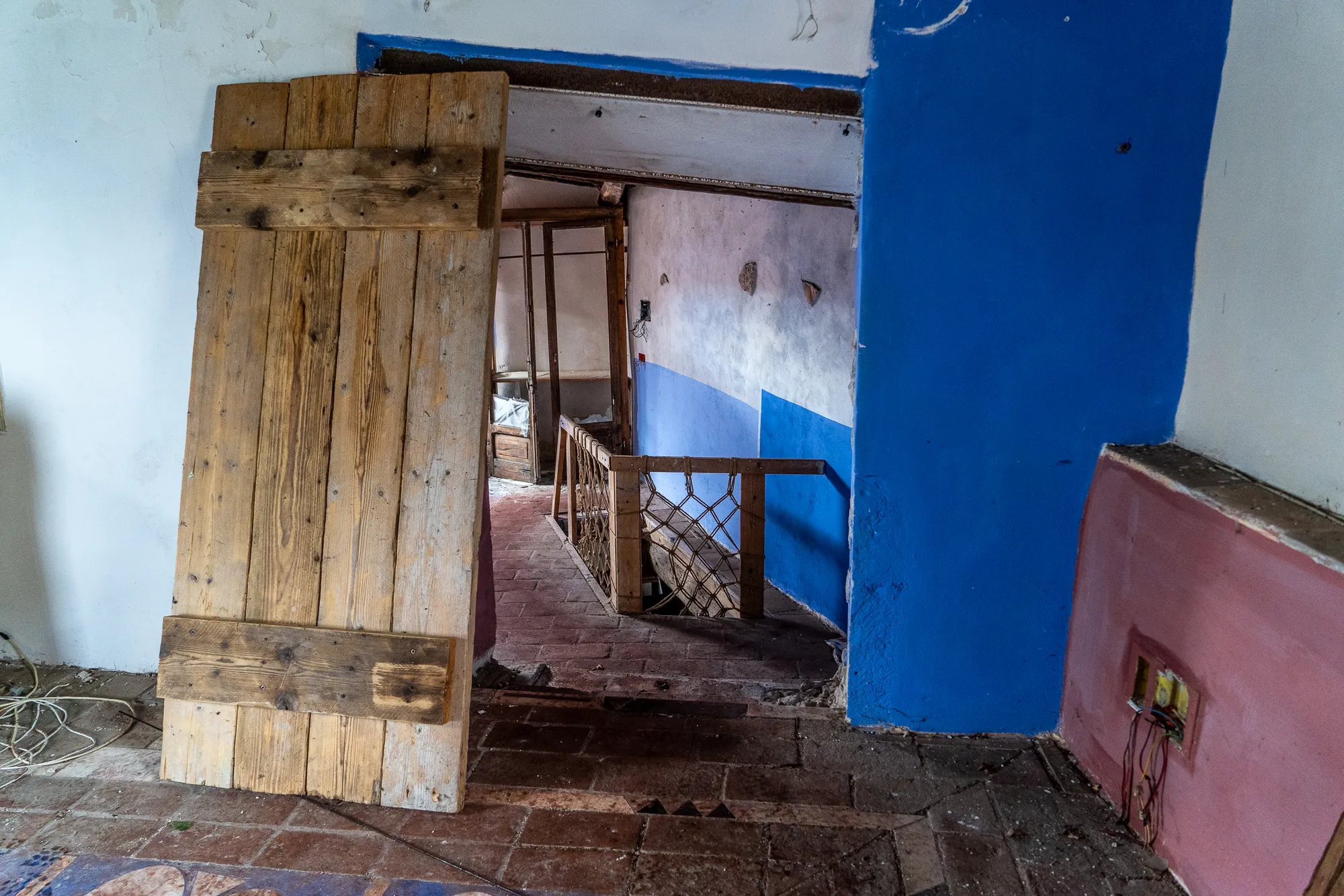 Holztor im Eingang eines verfallenen Hauses mit blauen und rosa Wänden