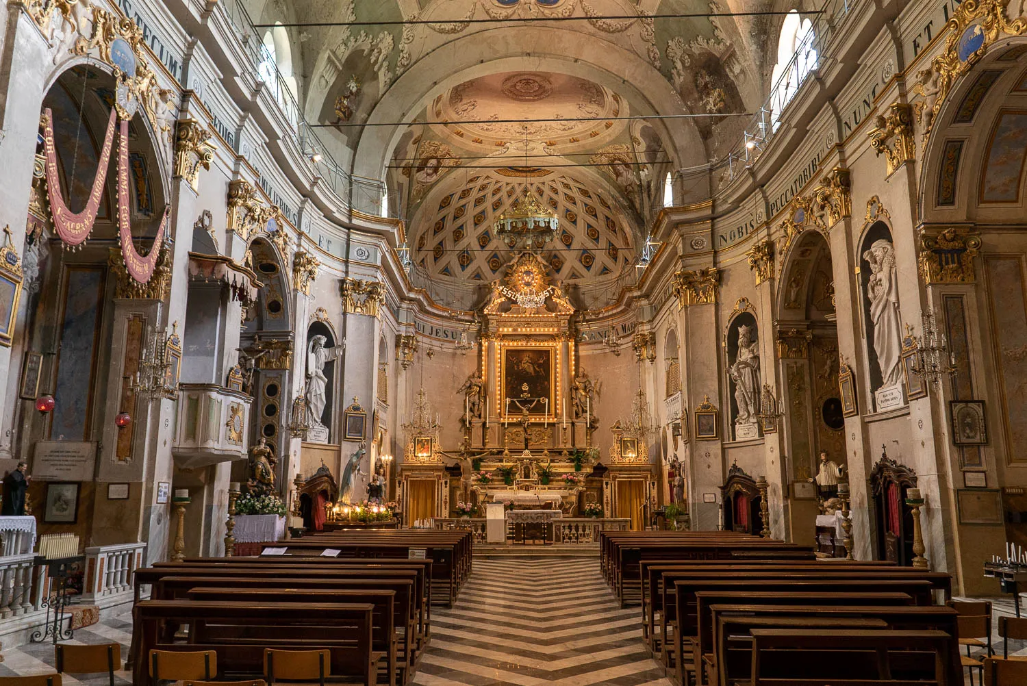 Innenraum einer barocken Kirche mit goldenem Altar und Holzbänken