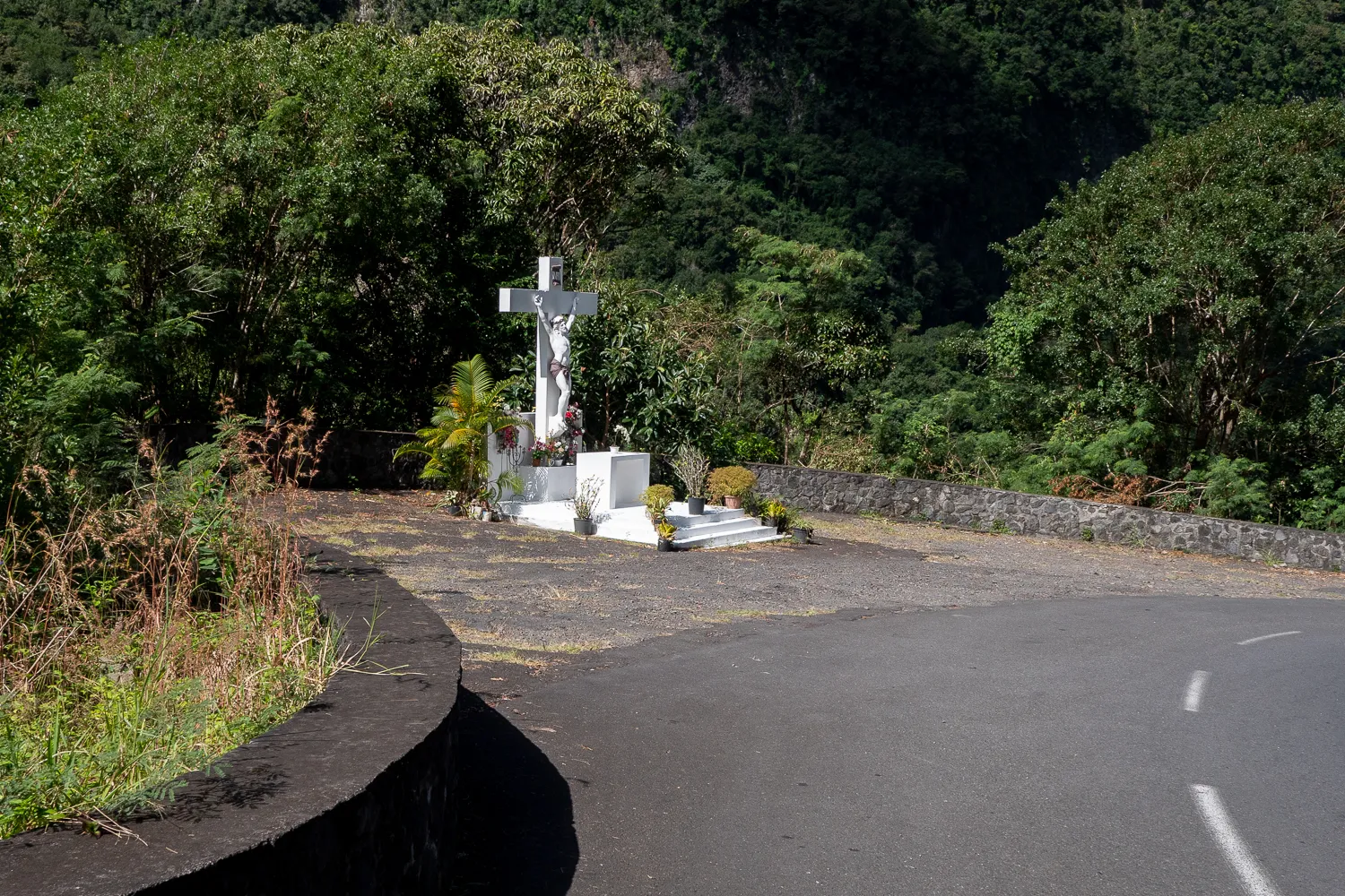 Weißes Kreuz an einer Straße im Wald