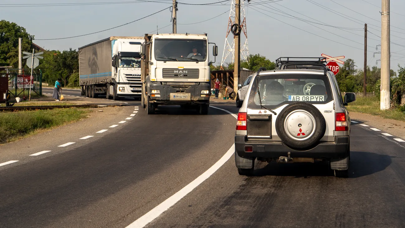 Zwei Lastwagen und ein SUV fahren auf einer Straße mit weißer Markierung.
