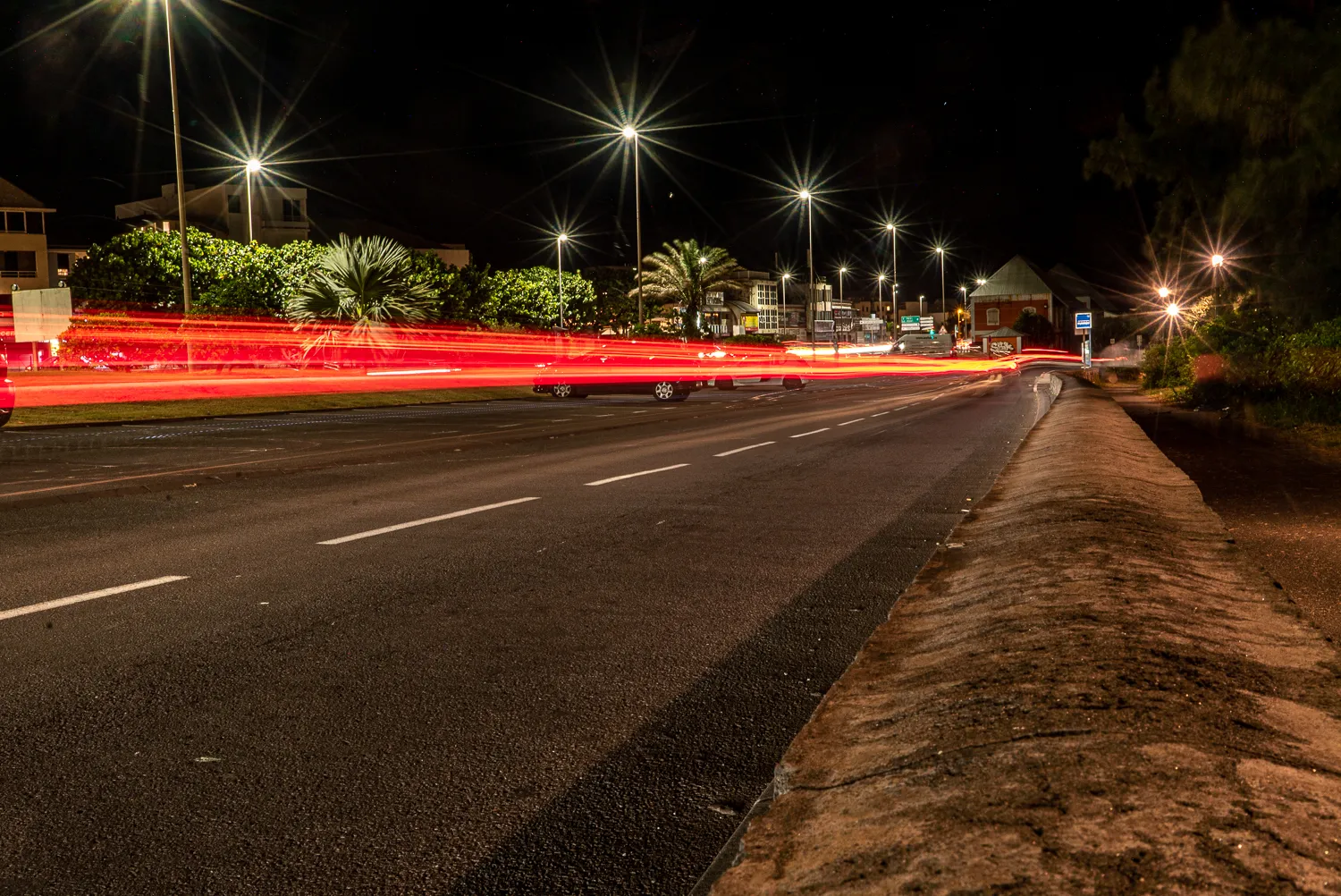 Nachtansicht einer Straße mit Lichtspuren von Fahrzeugen und Straßenlaternen