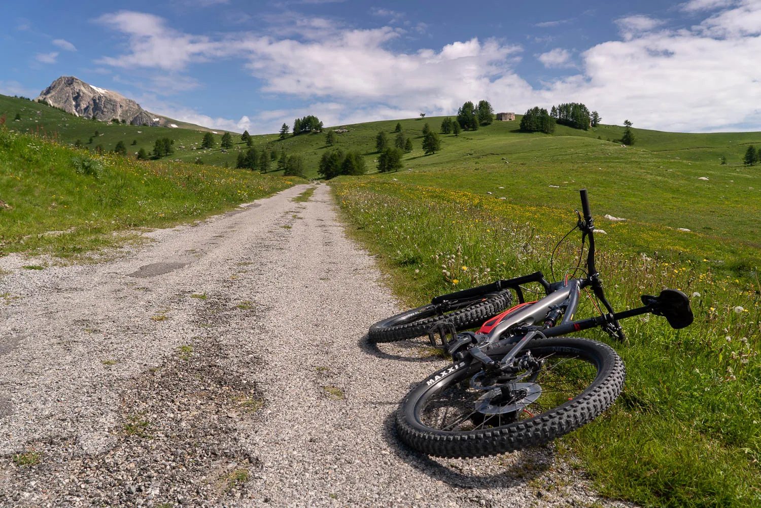 Mountainbike liegt auf Kiesweg in grüner Landschaft mit Berg im Hintergrund