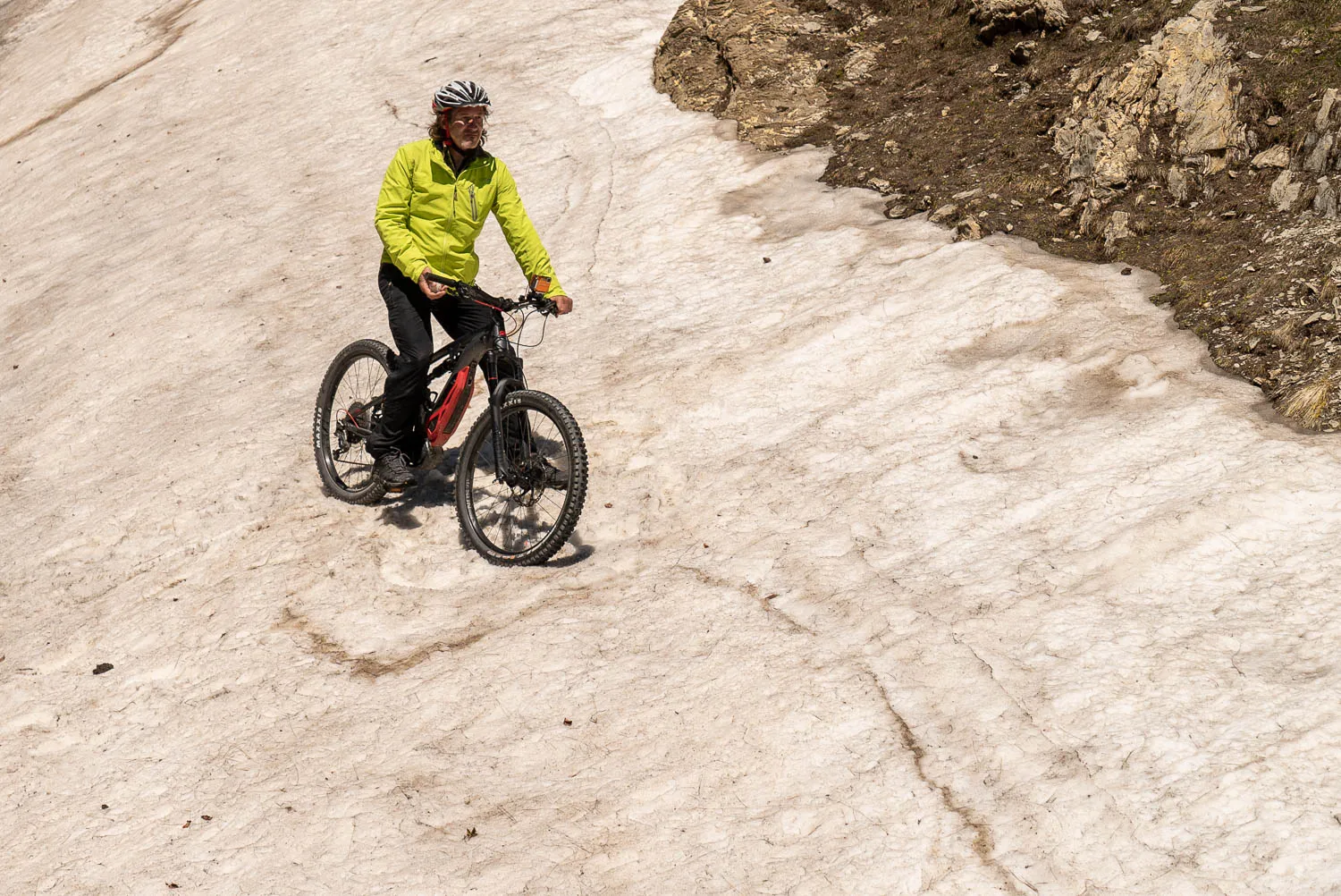 Mann fährt Mountainbike auf schneebedecktem Bergpfad