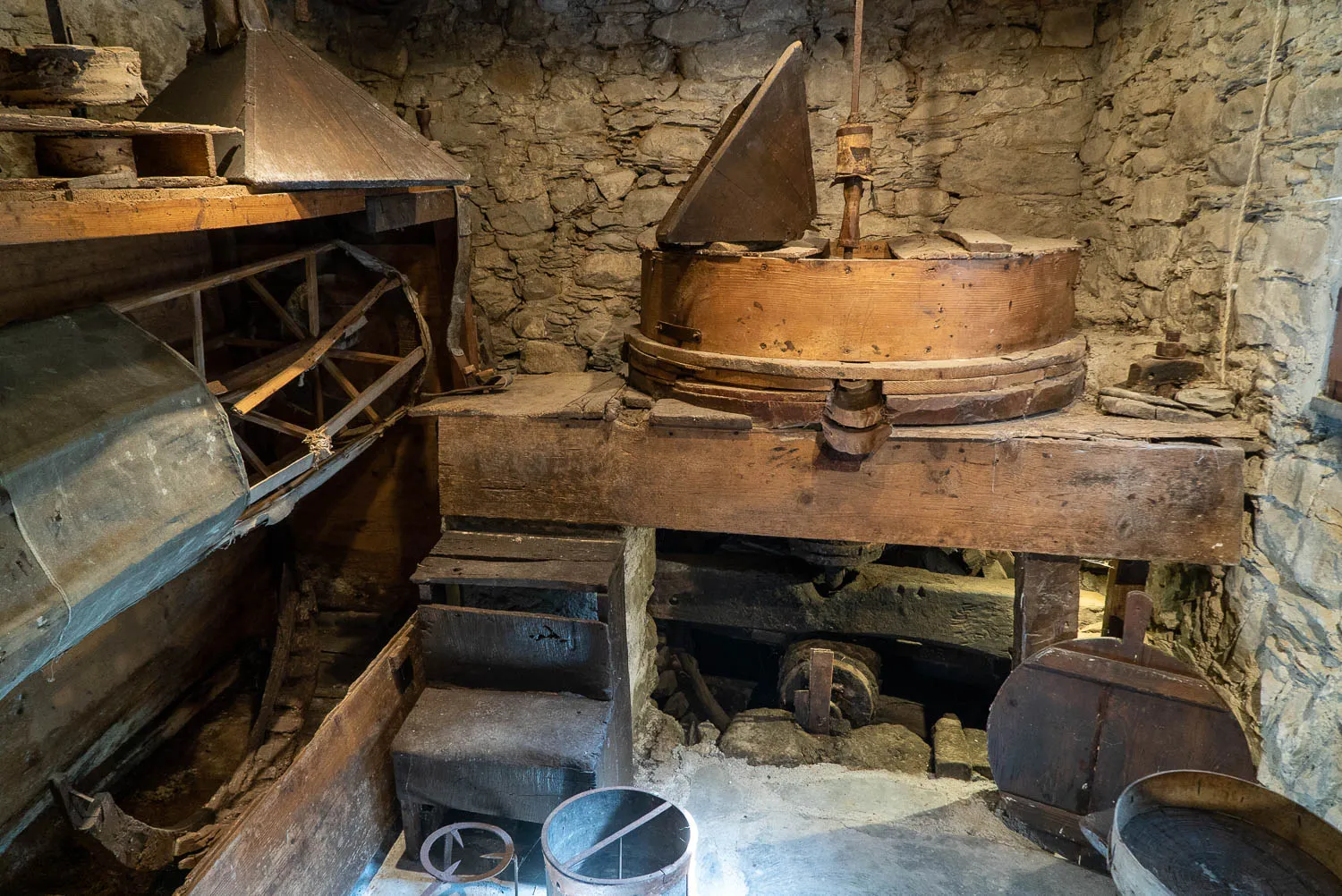 Alter hölzerner Mühlenkranz in Steinmauerwerk, rustikale Werkstatt mit Holzmaschinen.