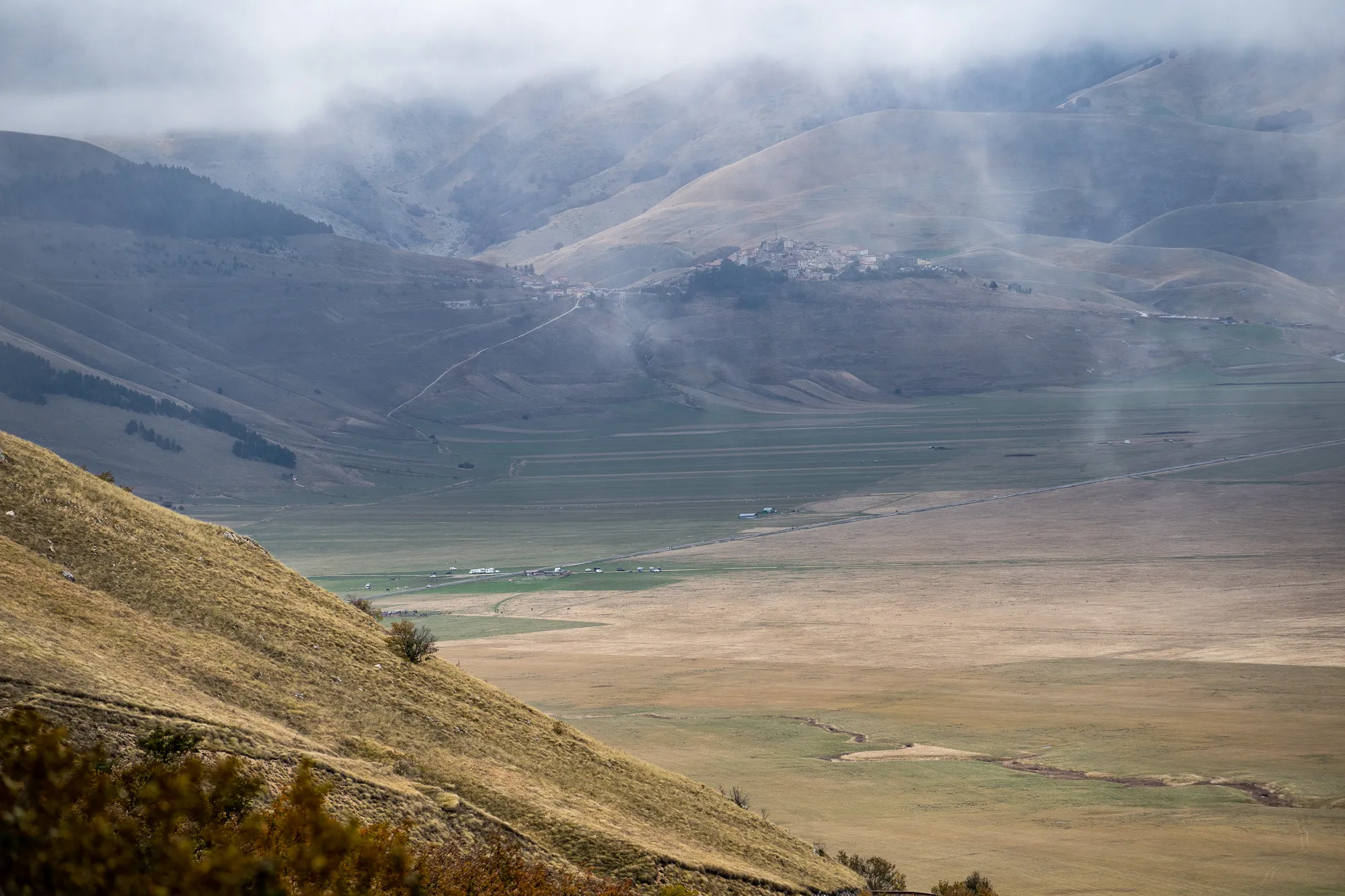 Berge und Tal unter Nebel, Sicht auf entferntes Dorf