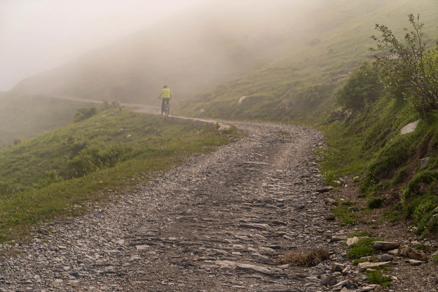 Radfahrer fährt auf steinigem Pfad durch dichten Nebel auf Hügel