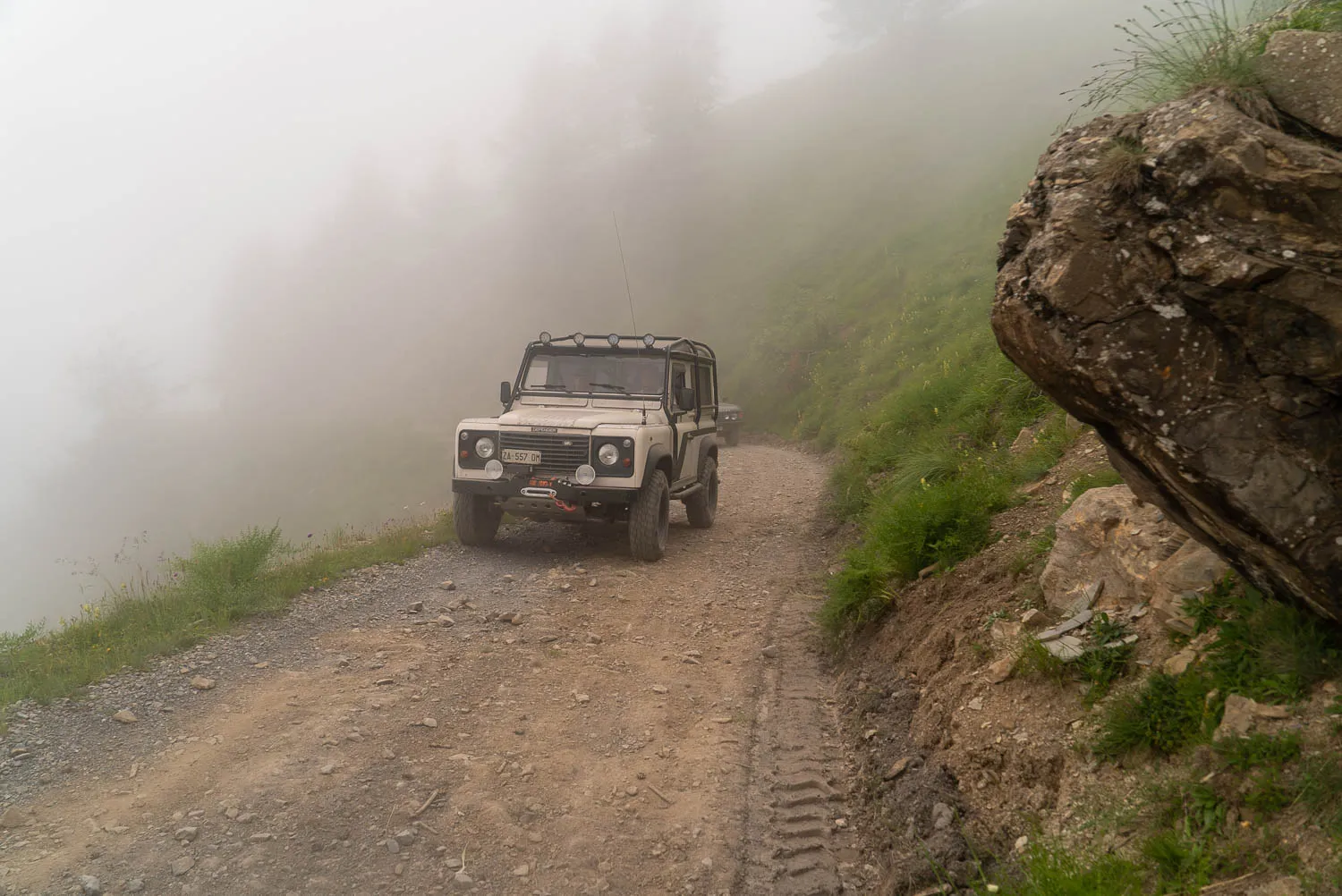 weißer offroad-wagen auf steinigem weg im dichten nebel
