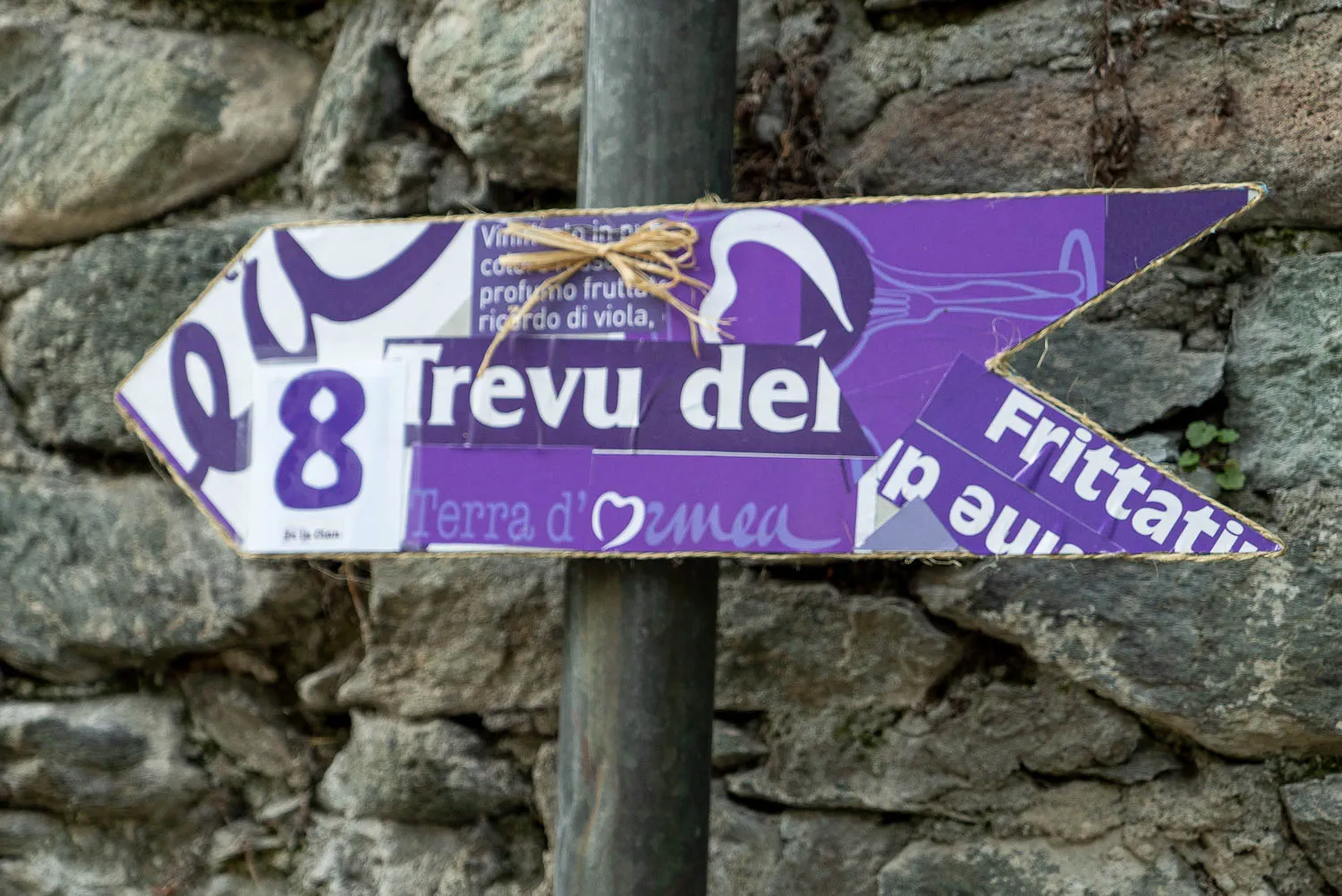 Pfeilschild mit Nummer 8 und Text 'Trevu del' vor Steinmauer