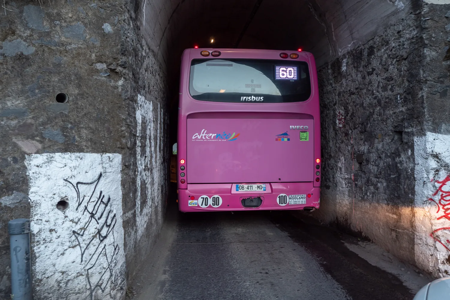 Pink Bus fährt durch Stein tunnel mit Graffiti an Wänden
