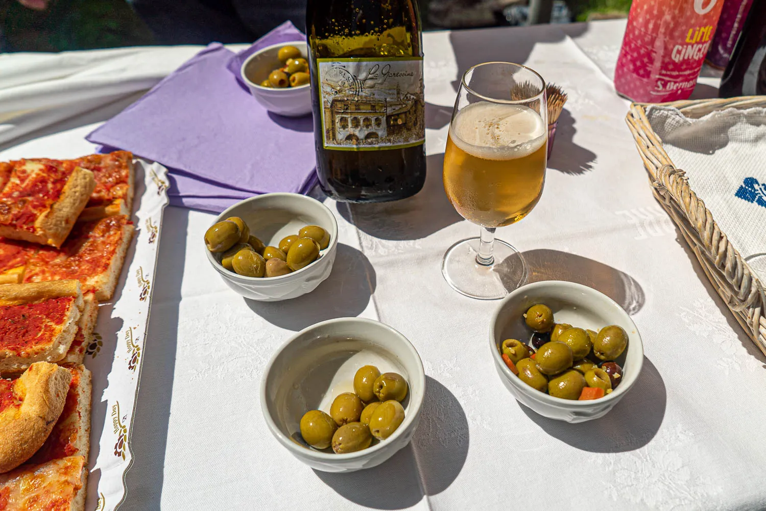 Tisch mit Pizza, Oliven, Wein und Bier im Freien