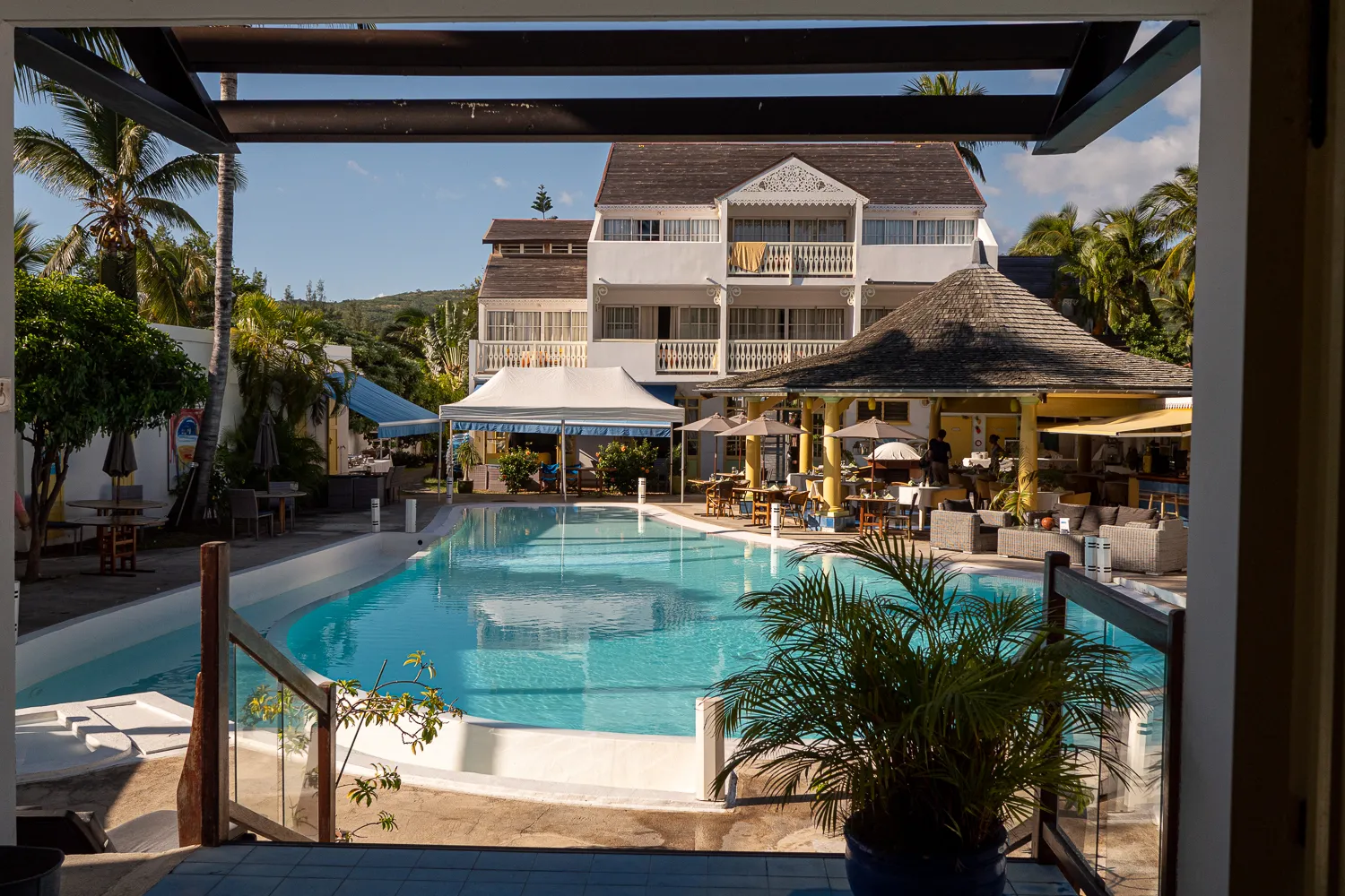 Poolbereich mit Hotelgebäude und Palmen im Hintergrund