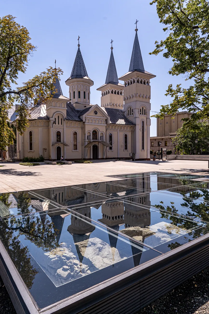 Reflexion der Kirche in einem Wasserbecken unter Bäumen