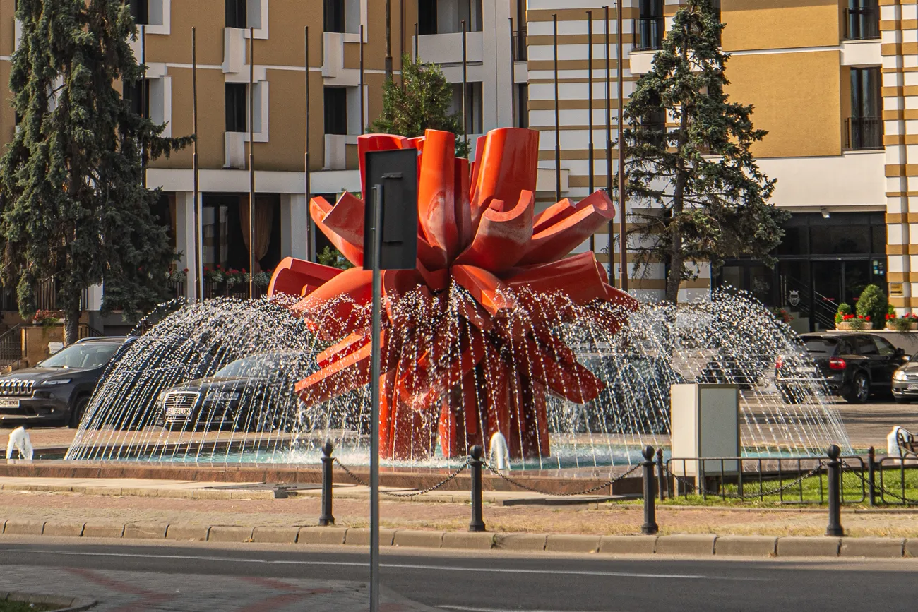 Roter Skulptur mit spritzendem Wasser in städtischem Platz