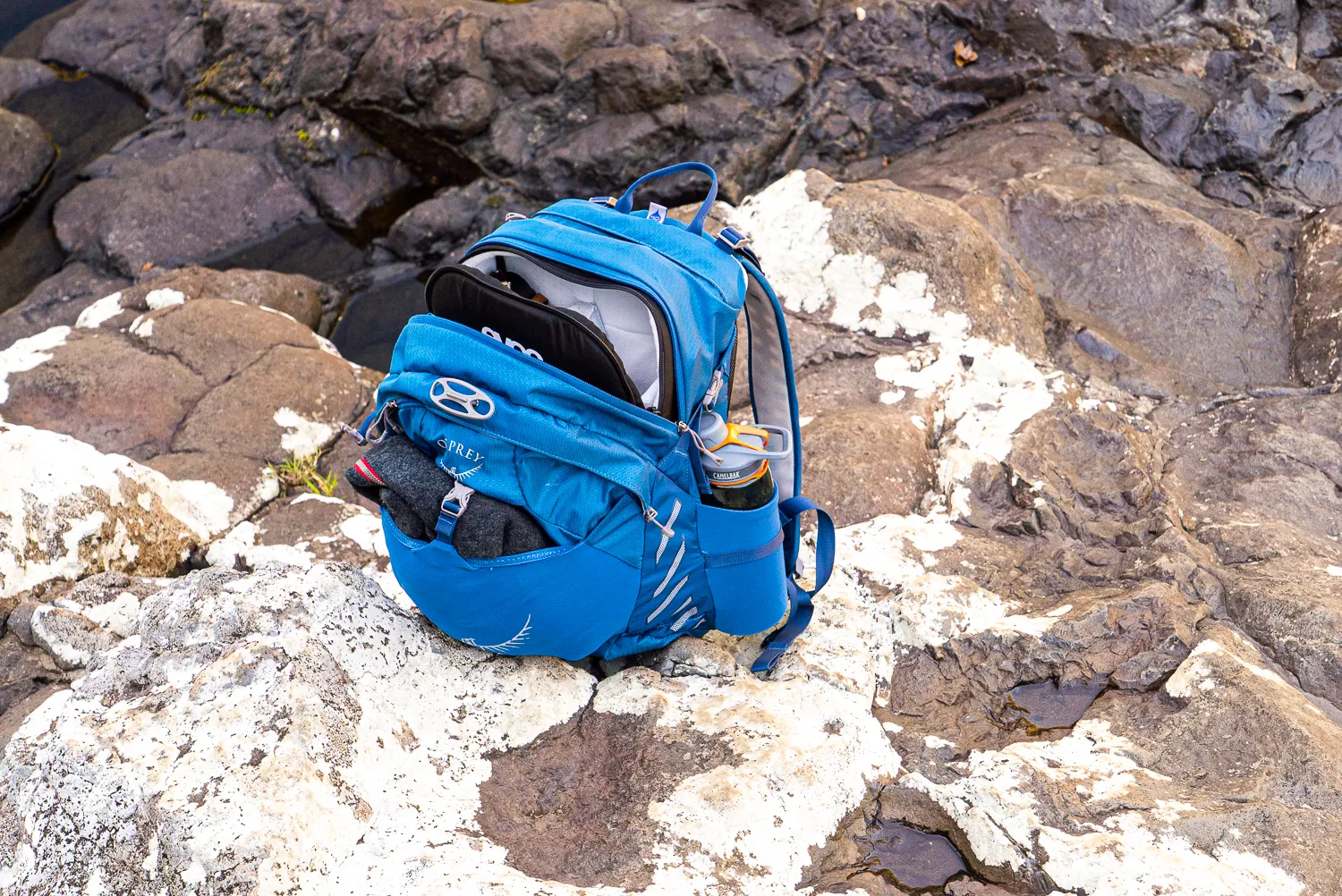 blauer rucksack auf felsen mit kies und moos