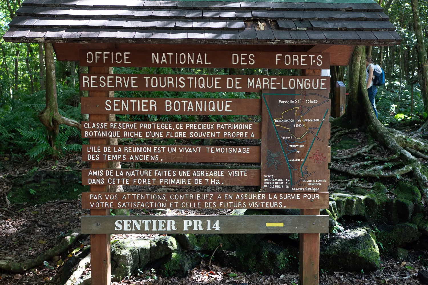 Holzschild im Wald mit Beschriftung Sentier Botanique und Karte