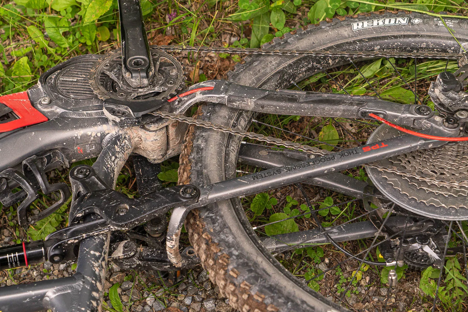 mud-covered mountain bike frame and wheel in grass