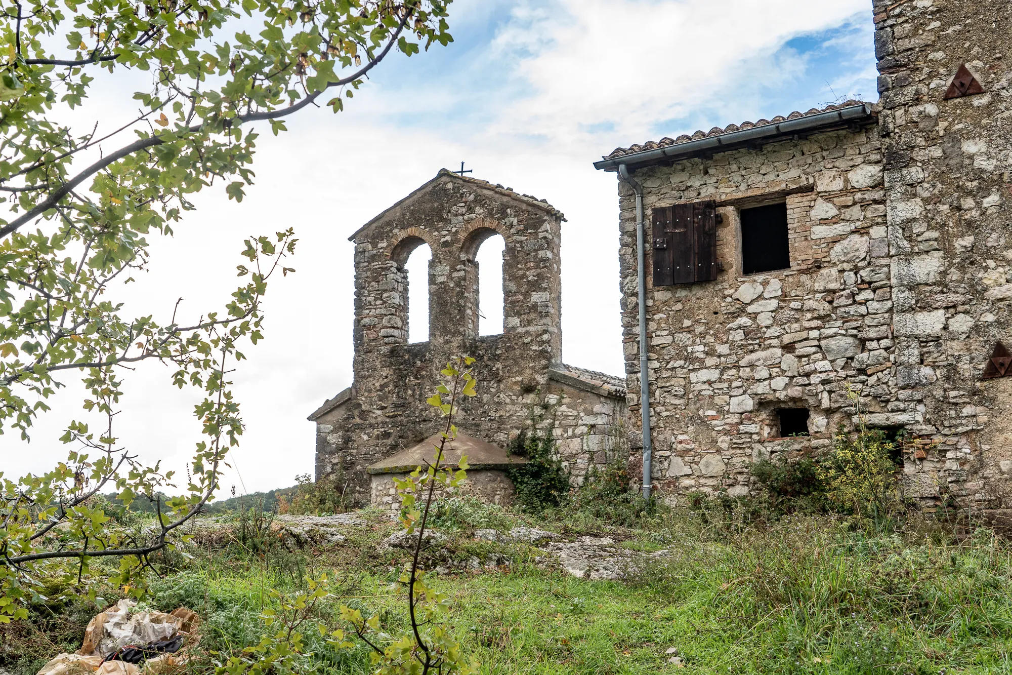 Alter Steinbau mit Glockenturm und umgebendem Grün