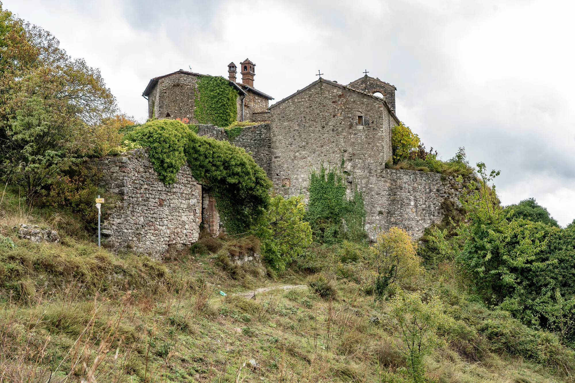 Steinhaus auf Hang mit Vegetation und bewölktem Himmel