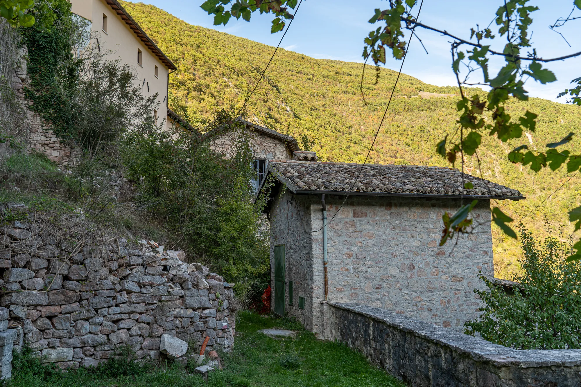 Steinhaus mit Steinmauer und grüner Tür in ländlicher Umgebung