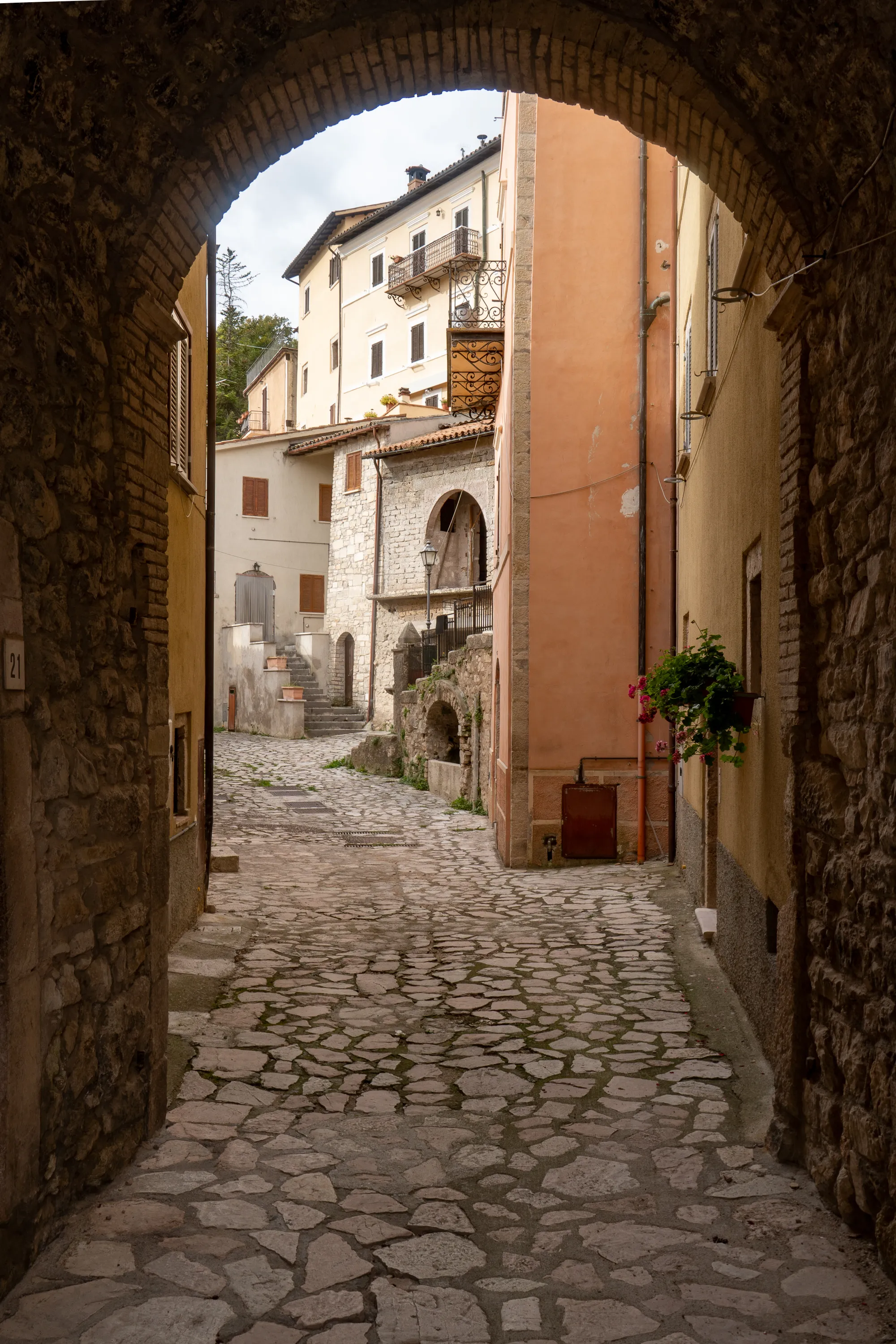 Steinpflastergasse unter Steinbogen mit historischen Häusern im Hintergrund