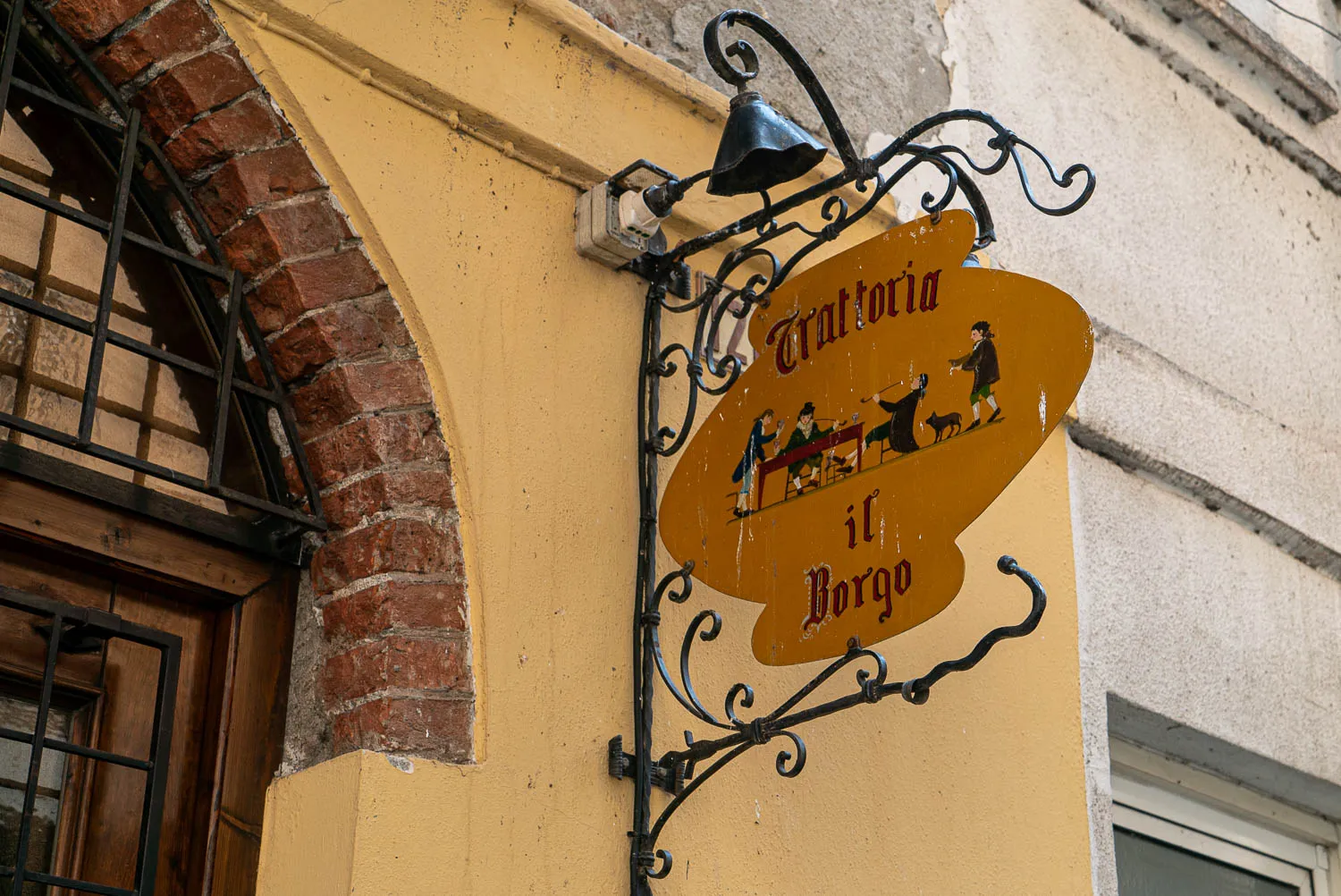 Gelbes Schild mit Schrift und Figuren an Hauswand