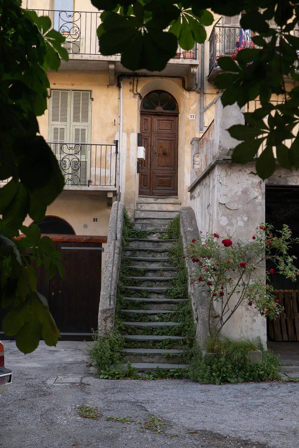 Steinerne Treppe zwischen alten Häusern mit Balkonen und roten Rosen.