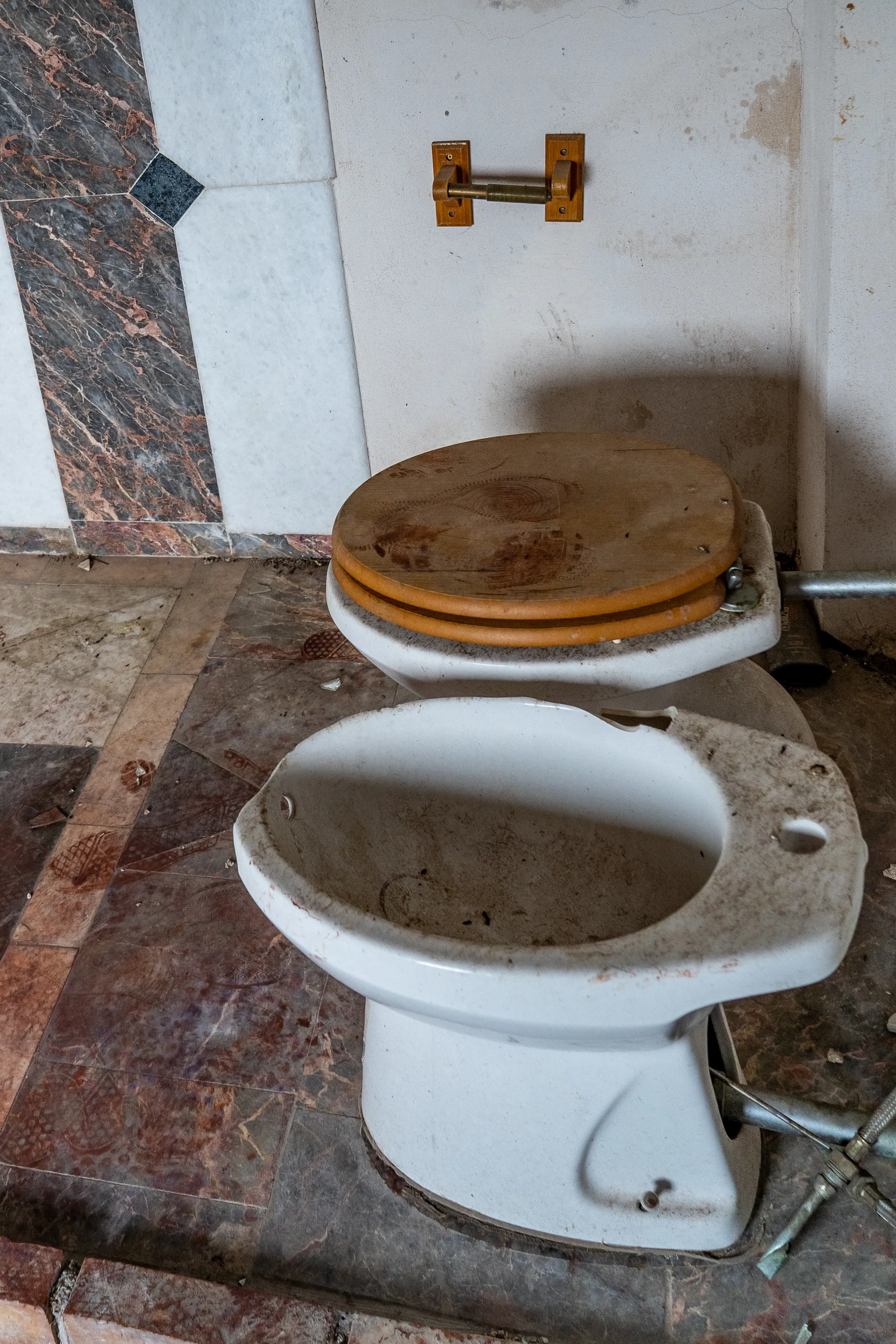 Verfallene Toilette in maritimer Wandverkleidung und Fliesenboden